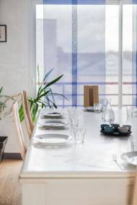 una mesa blanca con platos y vasos. en "SUITE-HOME 44600" Apt d'exception 3 Etoiles, en Saint-Nazaire