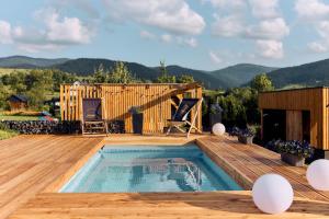 a swimming pool on a wooden deck with a house at Gorczańskie Wzgórze in Niedźwiedź
