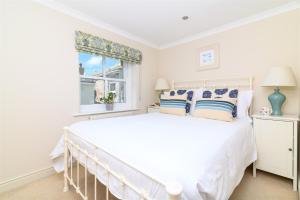 a white bedroom with a large bed and a window at Mousehole Cottage in Penzance