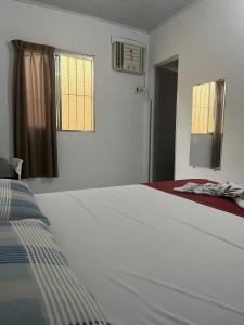 een witte slaapkamer met een bed en twee ramen bij Maragogi - Casa com piscina in Maragogi