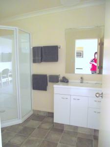 La salle de bains est pourvue d'un lavabo, d'un miroir et d'une douche. dans l'établissement Panorama Motor Inn, à Te Kuiti