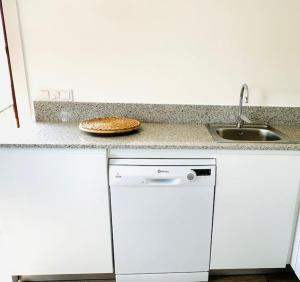 a white kitchen with a sink and a dishwasher at Apto Pedreña Golf y Surf in Pedreña +16 photos