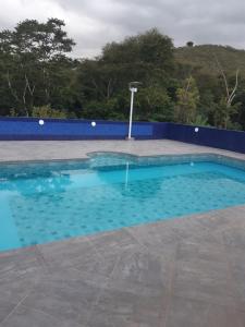 a swimming pool with blue water in front of a blue wall at Sitio Tripans Paraiso dos Sonhos in Igaratá