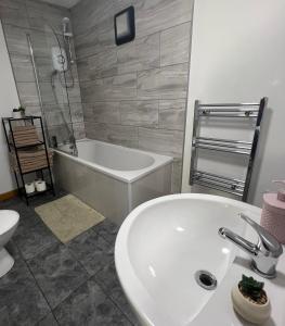 a bathroom with a sink and a tub and a toilet at The EliteApex in Manchester +5 photos