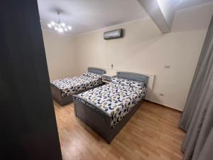 two beds in a room with wooden floors at Cairo in Cairo