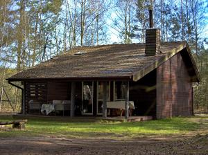 a log cabin with a porch and a fireplace at Leśna Chata in Bierzów