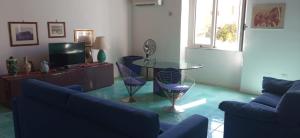 een woonkamer met blauwe banken en een glazen tafel bij Ca' da Mariolina in Carloforte +9 foto's