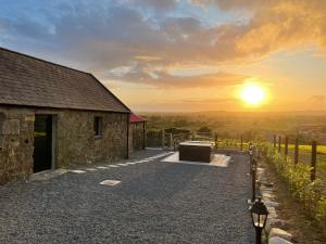 ein Steingebäude mit Sonnenuntergang im Hintergrund in der Unterkunft Cabra Cottage in Kilcoo