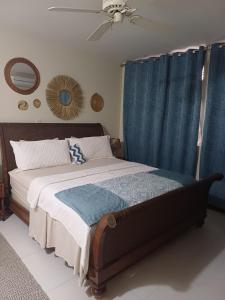 a bedroom with a bed with blue curtains and a fan at royal at courtleigh towers in Kingston