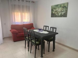 a dining room table with chairs and a red couch at La caleta in Oropesa del Mar