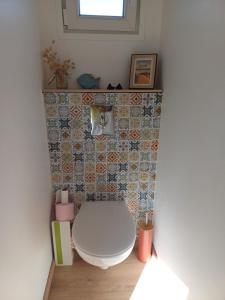 a bathroom with a toilet and a tile wall at Romanjo in Agon Coutainville