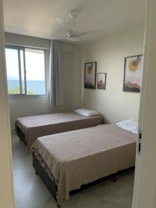 duas camas em um quarto com janela em Ap centro de Guarapari com as melhores vistas!!! em Guarapari