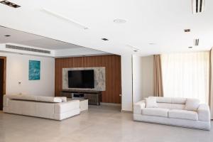 a living room with two white couches and a television at Hacienda Bay Villa with private pool in El Alamein