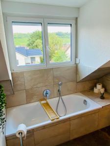 a bath tub in a bathroom with two windows at Design-Apartment II Klimaanlage I Basel 8 km I Boxspring I Nespresso in Weil am Rhein