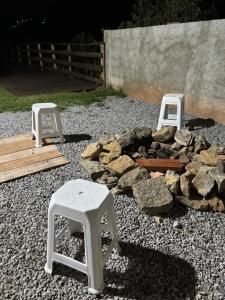 a fire pit with two stools and a pile of rocks at Recanto do sol in Extrema