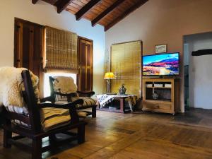 ein Wohnzimmer mit einem Flachbild-TV und einem Stuhl in der Unterkunft Casa en Sierras de Córdoba, Villa la Bolsa. in La Bolsa