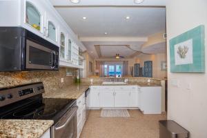 a large kitchen with white cabinets and a sink at Lawson Rock - Angelfish 101 condo in Roatan
