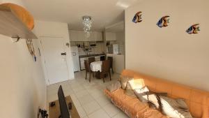 a living room with a couch and a kitchen at Confortável apartamento perto de praias - Bertioga in Bertioga