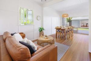 a living room with a brown couch and a table at Moffat Beach Entertainer with Kids Retreat & Walk to Beach in Caloundra +38 photos