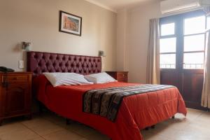 a bedroom with a red bed and a window at Alto Colonial in Salta