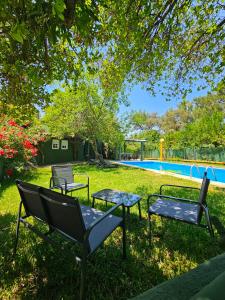 a yard with chairs and a table and a pool at Finca rural Labriega del hueznar in Cazalla de la Sierra