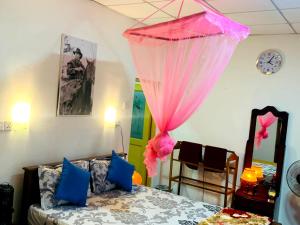 a bedroom with a bed with a pink curtain at Ella Willow Cottage in Ella