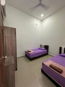 two beds in a room with purple sheets and a door at Homestay Kemaman Fyna08 Semi-D, 4 Bedrooms Dekat Pantai Kijal in Kijal +8 photos