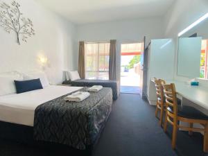 a hotel room with a bed and a desk and a desk at Bundaberg Spanish Motor Inn in Bundaberg