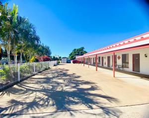 an empty street next to a building with palm trees at Bundaberg Spanish Motor Inn in Bundaberg