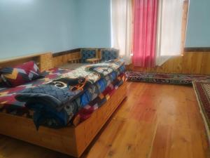 a bedroom with a bed in a room with wooden floors at Manepa Homestay Kardang in Kyelang