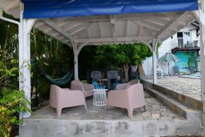 a patio with pink chairs and a blue canopy at LA DESIRADE SAINTE-ANNE in Sainte-Anne