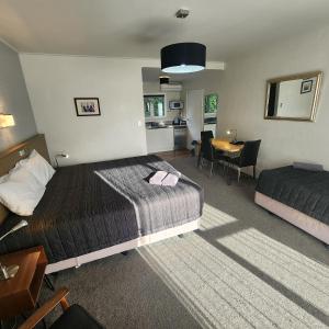a hotel room with two beds and a table at 16 Northgate Motor Lodge in New Plymouth