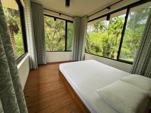 1 dormitorio con ventanas grandes y 1 cama con sábanas blancas en Willow's Abode, en Kandy
