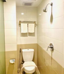 a bathroom with a toilet and a shower with towels at Jakarta City Hotel in Jakarta