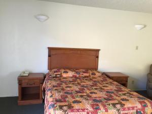 ein Schlafzimmer mit einem Bett und zwei Nachttischen in der Unterkunft Golden Hills Motel in Tehachapi