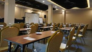 a conference room with tables and chairs and a whiteboard at OPI Indah Hotel in Palembang