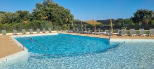 una grande piscina blu con sedie e sedie di LE COTTAGE DE LYXIE-Nature et sports a Talmont
