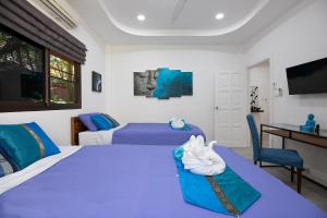 a bedroom with two beds and a desk and a television at Villa Paradise Island in Rawai Beach