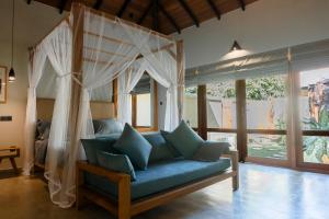 a living room with a blue couch with a canopy at The Spice Trail in Arugam Bay