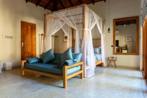 a living room with a blue couch and a canopy bed at The Spice Trail in Arugam Bay