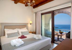 a bedroom with a bed with a view of the ocean at Stefanos Village Hotel in Plakias