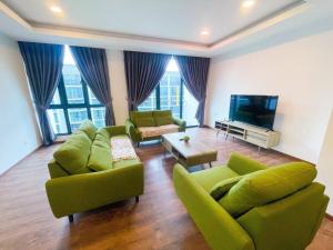 sala de estar con muebles verdes y TV de pantalla plana en Jazz Suite Vivacity Kuching, en Kuching