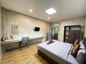 a bedroom with a bed and a desk in it at บ้านต้นไม้เพลส อุทัยธานี in Uthai Thani