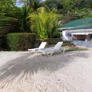 Dos sillas blancas sentadas en la playa frente a una casa. en L'Escapade Beach Villa, en Victoria