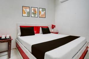 una camera da letto con un letto bianco con cuscini neri e rossi di Hotel O by OYO The King Heaven a Bewar