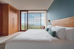 a large white bed in a room with a large window at Selong Selo Resort and Residences in Selong Belanak