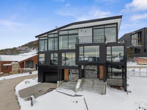 a house in the snow with glass at Luxury KH Chalet in Mount Hotham