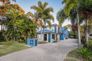 a blue house with palm trees in front of it at Swell Life - Spacious 3-Bedroom Retreat in Central Agnes Water in Agnes Water