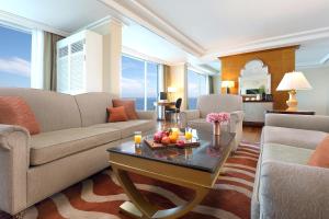 a living room with a couch and a table with fruit on it at Ramada Plaza by Wyndham Jeju Ocean Front in Jeju