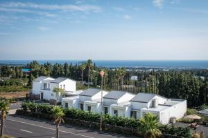 a row of white houses with the ocean in the background at La Pause Pension in Seogwipo